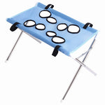 Blue foldable pet bathing stand with a blue mesh grooming hammock, eight black-edged openings, silver folding frame, black straps, and white corner caps on a white background.
