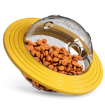 Yellow interactive pet treat dispensing toy with a clear transparent dome and brown kibble inside on a clean white background.