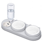 Light gray gravity pet feeder with a clear water reservoir and two white ceramic bowls on a white background.
