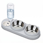 Light gray gravity pet feeder with a clear water reservoir and two stainless steel bowls on a white background.

