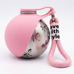 Pink portable dog water bottle with a stainless steel body decorated with bow patterns and a matching pink wrist strap.
