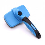 Blue and black self-cleaning dog and cat grooming brush shown from the smooth back side with its round cleaning button and ergonomic handle on a white background.

